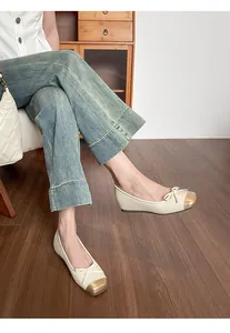 Vista dettagliata di eleganti ballerine beige con punta dorata e fiocco delicato ai piedi