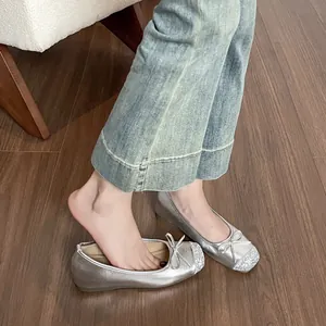 Eleganti ballerine argento con fiocco e punta glitterata su un pavimento in legno scuro