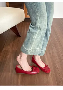 Close-up view of red French style ballet flats with elegant bow detail on a wooden floor