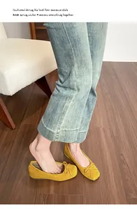 Detailed view of elegant yellow suede ballet flats with bow accent and hidden wedge