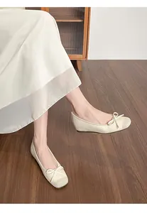 Close-up of elegant cream ballet flats featuring a bow and glitter toe cap detail