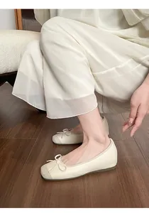 Close-up of elegant cream French-style ballet flats with bow detail and hidden wedge