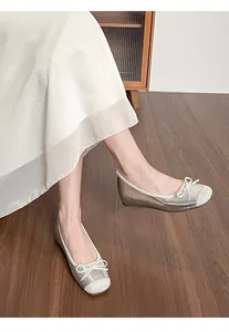 Close-up detail of silver ballet flats with a cute bow on a model in a cozy setting