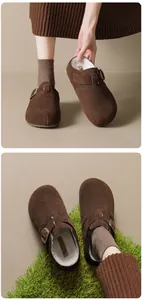 Close-up of brown suede fur-lined clogs with metal buckle and platform sole
