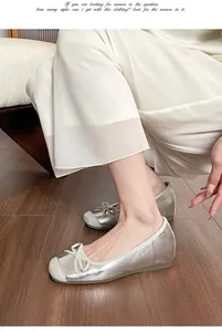 Detailed view of silver ballet flats featuring a bow and inner heightening sole.