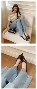 Detail shot of brown pointed-toe flats with double silver buckles on an Asian model.