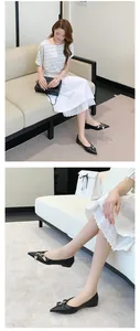 Detailed view of French style black pointed-toe flats with metal buckle decoration