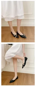 Detailed visual of black pointed-toe flats with silver buckles worn with a white dress