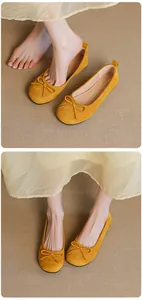 Close-up view of yellow suede ballet flats with elegant bow detail on a beige mat