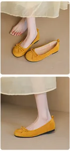 Close-up detail of yellow suede ballet flats featuring a decorative bow and soft sole