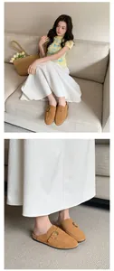 Detailed view of tan suede buckle mules styled with a long white skirt in a home setting