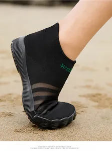 Vue détaillée de chaussures d'eau pieds nus en maille noire flexible sur sable de plage