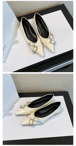Detailed side view of elegant cream pointed-toe flats featuring double metallic buckle straps
