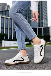 Close-up of white leather sneakers with black accents and gum sole on a model