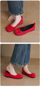 Detailed view of vibrant red ballet flats with bows paired with blue denim jeans