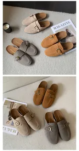 Close-up of suede mule slippers with adjustable buckle straps in multiple colors.