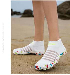 Détail de chaussures d'eau en maille blanche respirante avec semelles colorées sur plage