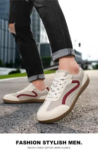 Detailed view of stylish white men's trainers with red accents and gum sole on pavement