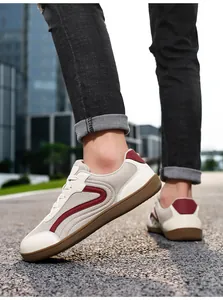 Professional detail shot of men's beige casual trainers with red stripes on a street