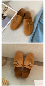 Close-up detail of stylish tan suede mules with decorative vintage metal buckle strap