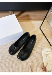 Nahaufnahme von stilvollen schwarzen Tabi-Ballerinas aus Leder mit geteiltem Zehenbereich