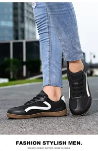 Close-up detail of black men's casual sneakers with white wave pattern on urban street.