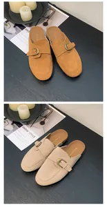 Close-up detail of stylish suede mule slippers with buckle straps in tan and beige colors