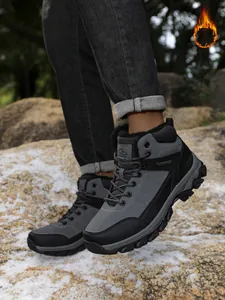 Close-up of men's fleece-lined hiking boots worn on rocky terrain for winter warmth.