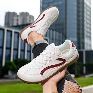 White leather German trainer sneakers for men with red stripe accents and gum sole