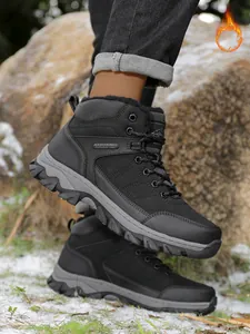Close-up view of black fur-lined hiking boots worn on a rocky and snowy outdoor trail