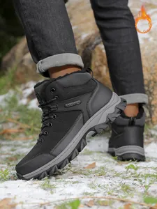 Detailed view of men's black winter snow boots with warm fleece lining in snowy terrain