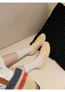 Scarpe da ginnastica stile ballerina beige in mesh con calze bianche su un divano.