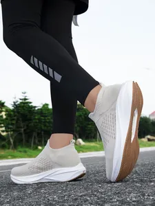 Side view of breathable beige slip-on walking sneakers worn on an outdoor road.