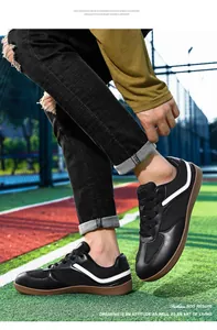 Vista detallada de zapatillas alemanas de cuero negro con rayas blancas en pista deportiva