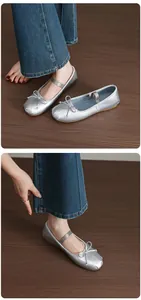 Detail of silver Mary Jane ballet flats with bow and elastic strap on denim background