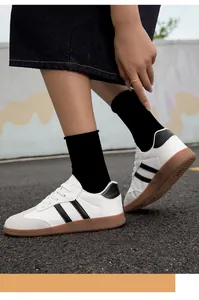 Detailed view of white German army trainer sneakers with gum soles on asphalt