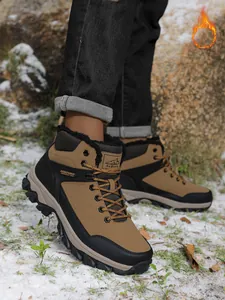 Close-up of men's winter hiking boots with warm fur lining in snowy outdoor setting