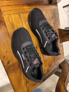 Close-up of black breathable mesh air cushion sneakers displayed on a wooden table