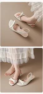 Λεπτομερής προβολή κομψών κρεμ πέδιλων slingback με φιόγκο και χαμηλό λεπτό τακούνι