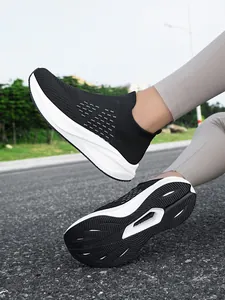 Detailed outdoor view of black breathable slip-on sneakers on a gray asphalt road