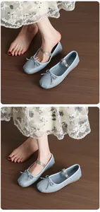 Close-up detail of blue Mary Jane ballet flats with bow and elastic strap on wood floor