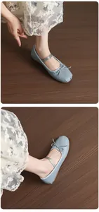 Light blue Mary Jane ballet flats with bow and elastic strap shown on wooden floor