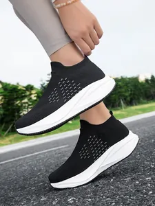 Lightweight breathable black slip-on knit sneakers for men and women on an outdoor path