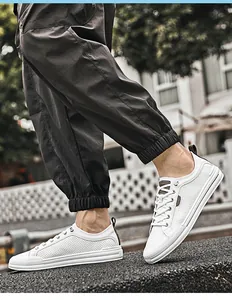 Détail de baskets décontractées blanches perforées pour hommes portées dans un look de rue