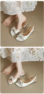 Λεπτομέρεια από κομψά λευκά πέδιλα slingback με φιόγκο και μια φούστα με λουλούδια.