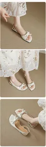 Λεπτομερής προβολή κομψών λευκών slingback πέδιλων με φιόγκο και άνετο λεπτό τακούνι.