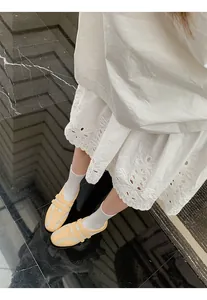 Dettaglio delle sneakers ballerina giallo pallido con tacco interno e abito in pizzo