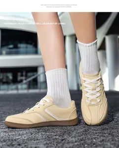 Primo piano di sneakers GAT in pelle beige con calzini bianchi su asfalto.