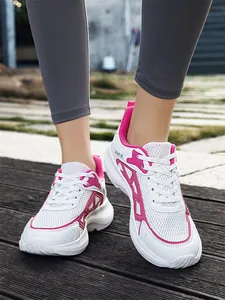 Close-up of white and pink breathable mesh sneakers worn outdoors on a wooden deck.