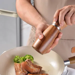 Manual solid wood spice grinder for freshly ground pepper shown in kitchen use scene